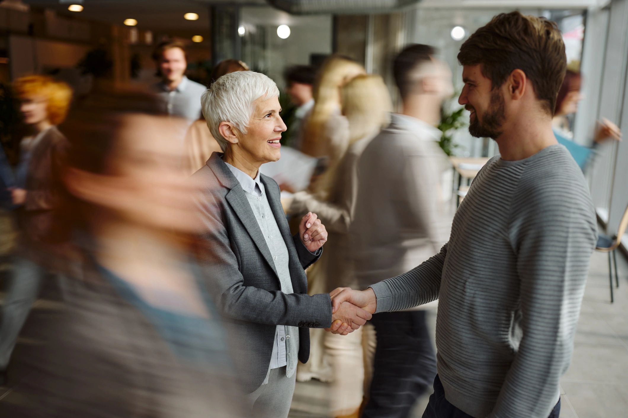 People greeting one another with a handshake in a welcoming setting